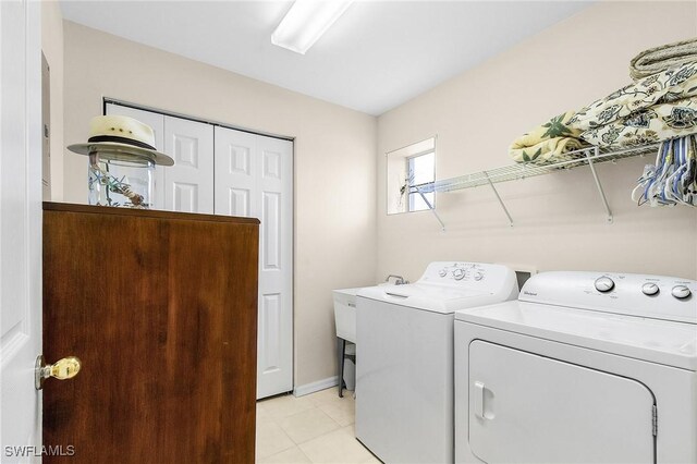 laundry room with separate washer and dryer, light tile patterned floors, and baseboards
