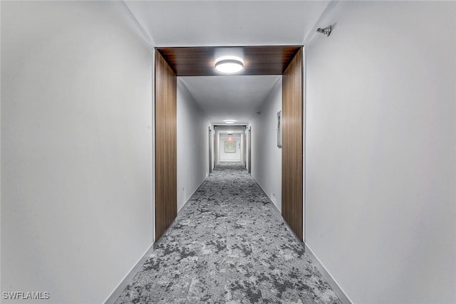 hall with baseboards and carpet floors