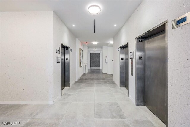 corridor featuring elevator and baseboards