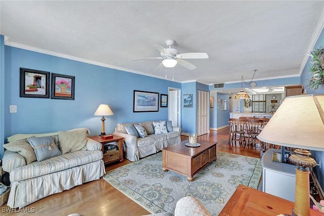 living room featuring wood finished floors, a ceiling fan, crown molding, and baseboards