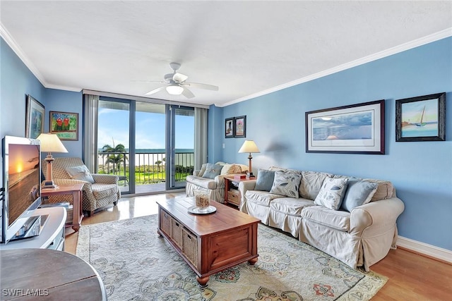 living area featuring ornamental molding, ceiling fan, light wood-style flooring, baseboards, and a wall of windows
