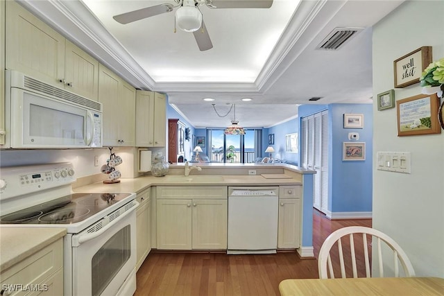 kitchen featuring white appliances, a peninsula, light countertops, dark wood-style flooring, and ornamental molding