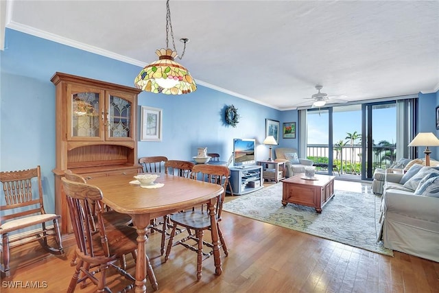dining room featuring ornamental molding, wood finished floors, a wall of windows, and a ceiling fan