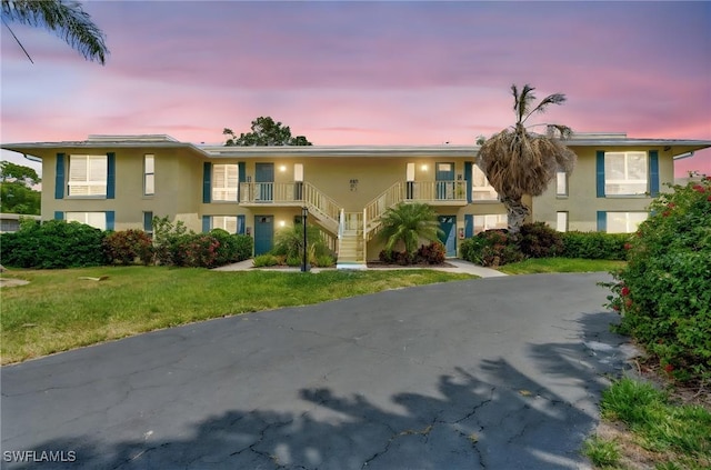 300 Palm Dr Unit 402, Naples, FL 34112 - view of property featuring stairway, stucco siding, a lawn, and driveway