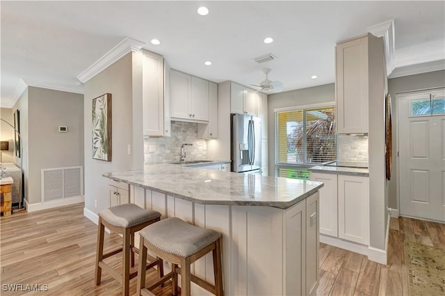 300 Palm Dr Unit 402, Naples, FL 34112 - kitchen featuring stainless steel refrigerator with ice dispenser, a sink, crown molding, light wood-type flooring, and decorative backsplash