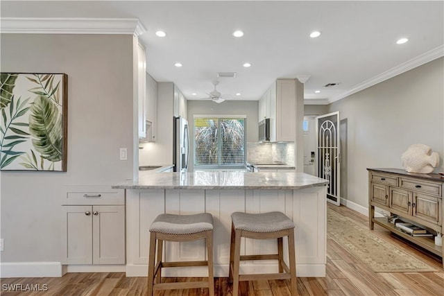 300 Palm Dr Unit 402, Naples, FL 34112 - kitchen with appliances with stainless steel finishes, crown molding, light stone countertops, a peninsula, and tasteful backsplash