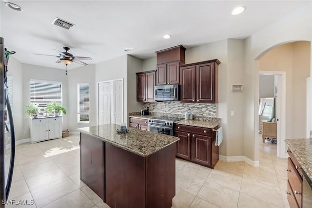 1302 SW 20th St, Cape Coral, FL 33991 - kitchen featuring stainless steel appliances, arched walkways, a ceiling fan, backsplash, and light stone countertops