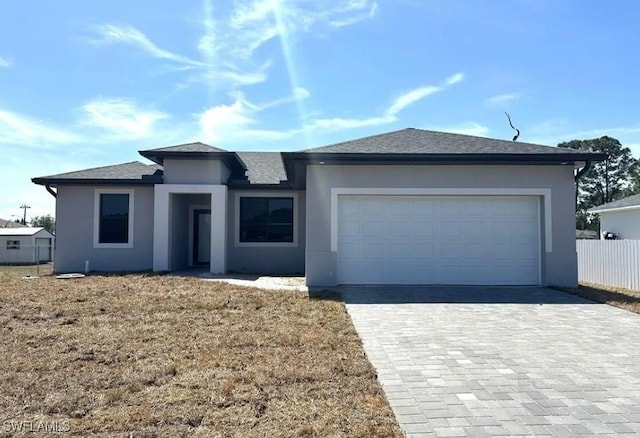 view of front of home featuring decorative driveway, stucco siding, a garage, and fence