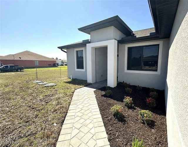 doorway to property with stucco siding and a lawn