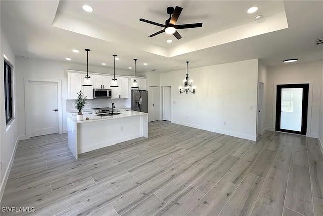kitchen featuring stainless steel appliances, a raised ceiling, ceiling fan, baseboards, and recessed lighting