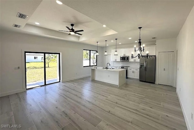 kitchen with appliances with stainless steel finishes, open floor plan, baseboards, a chandelier, and a sink
