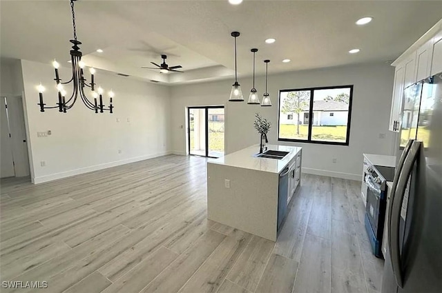 kitchen with appliances with stainless steel finishes, a sink, a ceiling fan, baseboards, and light wood finished floors