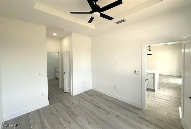 empty room featuring wood finished floors, a ceiling fan, baseboards, a tray ceiling, and recessed lighting