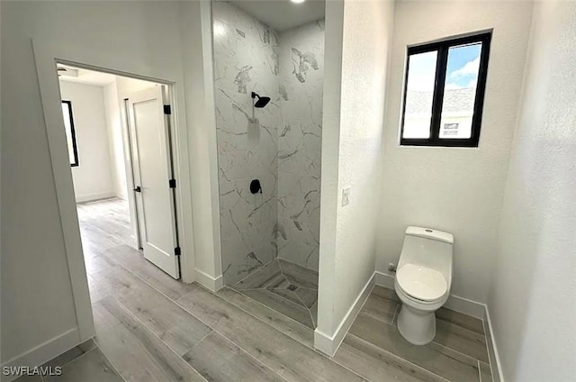 full bathroom featuring a marble finish shower, toilet, wood finished floors, and baseboards