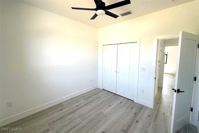 unfurnished bedroom with light wood-style floors, baseboards, a closet, and ceiling fan