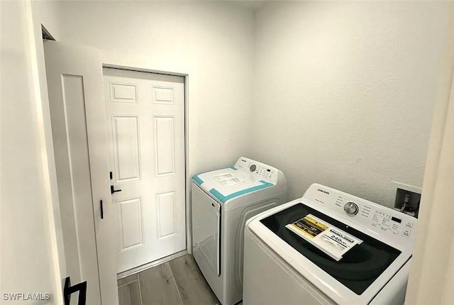 laundry area featuring washer and clothes dryer and wood finished floors