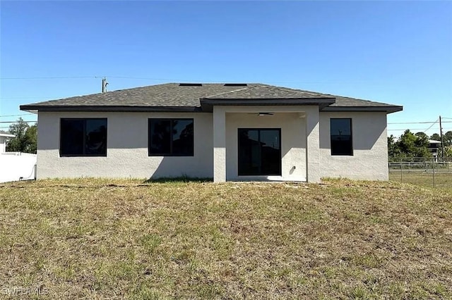 rear view of property featuring stucco siding and a shingled roof