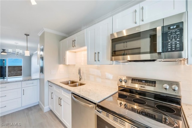 kitchen with stainless steel appliances, a sink, tasteful backsplash, white cabinets, and crown molding