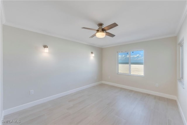 spare room featuring crown molding, ceiling fan, light wood-style floors, and baseboards