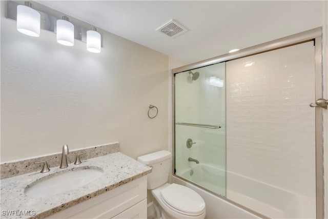 bathroom featuring toilet, bath / shower combo with glass door, and vanity
