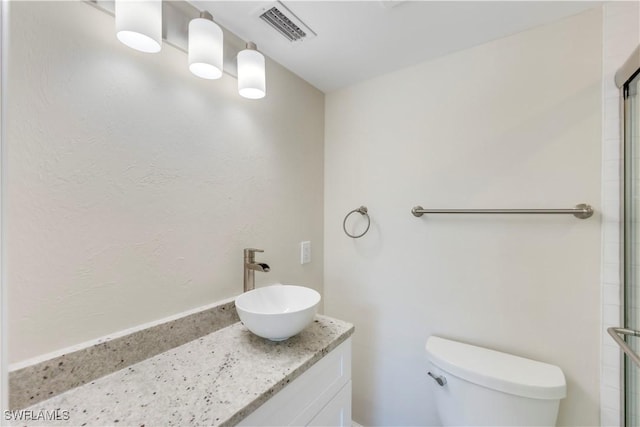 bathroom featuring toilet, a shower with door, and vanity