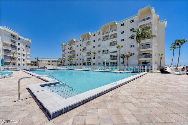 community pool with fence and a patio area