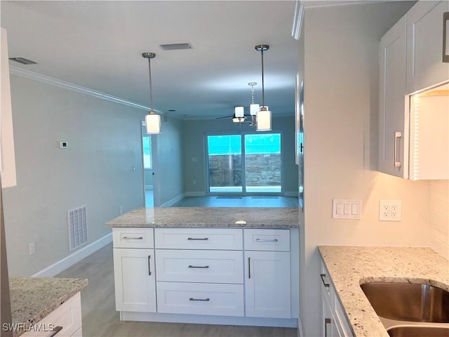 7400 Estero Blvd Unit 126, Fort Myers Beach, FL 33931 - kitchen with white cabinetry, ornamental molding, light wood-type flooring, ceiling fan, and light stone counters