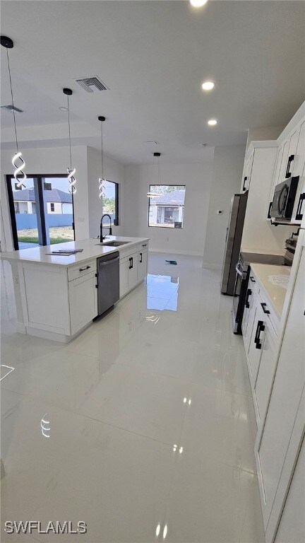 1214 Hibiscus Ave, Lehigh Acres, FL 33972 - kitchen featuring dishwashing machine, freestanding refrigerator, an island with sink, white cabinets, and recessed lighting