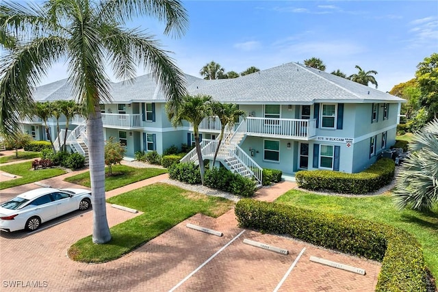 676 W Elkcam Cir Unit 1222, Marco Island, FL 34145 - view of building exterior featuring stairs and uncovered parking