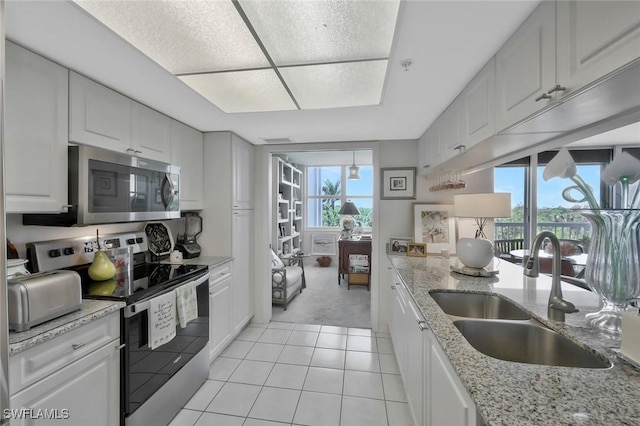 6573 Marissa Loop Unit 303, Naples, FL 34108 - kitchen featuring stainless steel appliances, a sink, light tile patterned floors, and white cabinetry