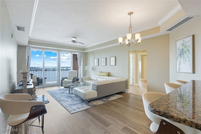 2745 1st St Unit 701, Fort Myers, FL 33916 - living area featuring a tray ceiling, a chandelier, a ceiling fan, wood finished floors, and ornamental molding