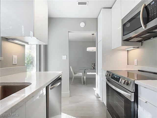 2544 1st St Unit 102, Fort Myers, FL 33901 - kitchen featuring stainless steel appliances, white cabinetry, modern cabinets, light stone counters, and baseboards