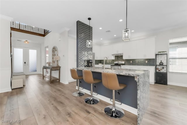 6619 Marbella Dr, Naples, FL 34105 - kitchen featuring stainless steel range with electric cooktop, crown molding, white cabinets, decorative backsplash, and light wood-type flooring