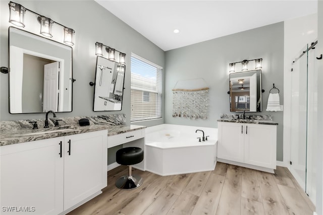 6619 Marbella Dr, Naples, FL 34105 - full bathroom featuring wood finished floors, a garden tub, two vanities, and recessed lighting