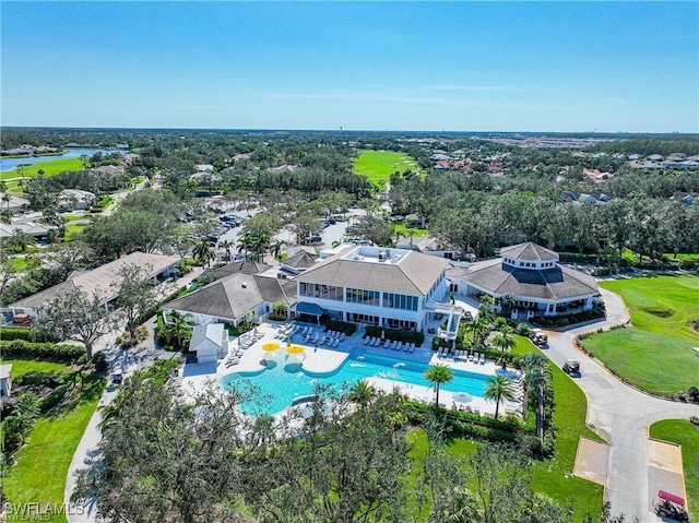 aerial perspective of suburban area featuring a pool, a large body of water, and a tree filled landscape