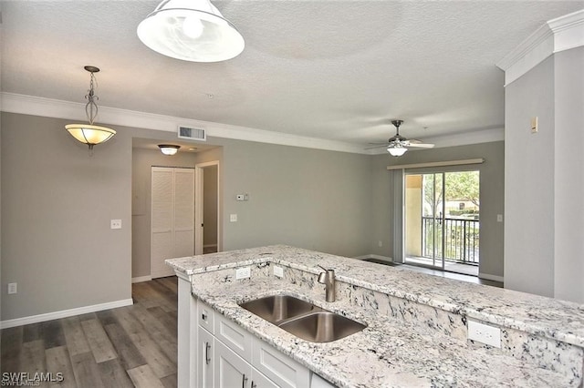 kitchen featuring a sink, baseboards, dark wood-type flooring, white cabinets, and decorative light fixtures