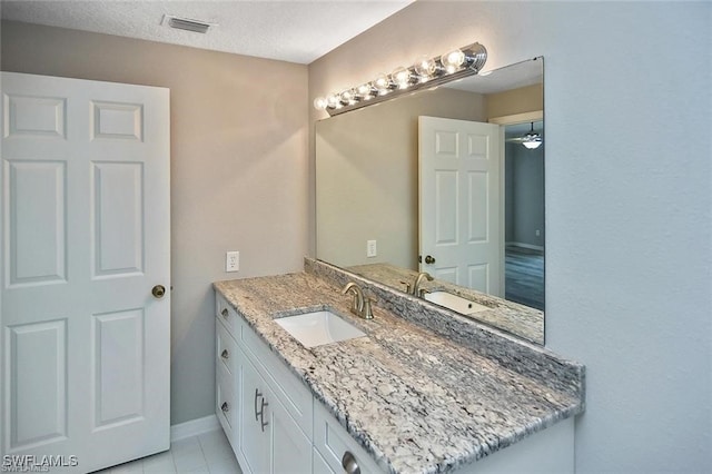bathroom featuring vanity, baseboards, tile patterned floors, and a textured ceiling
