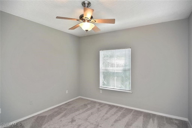 carpeted empty room featuring ceiling fan, baseboards, and a textured ceiling