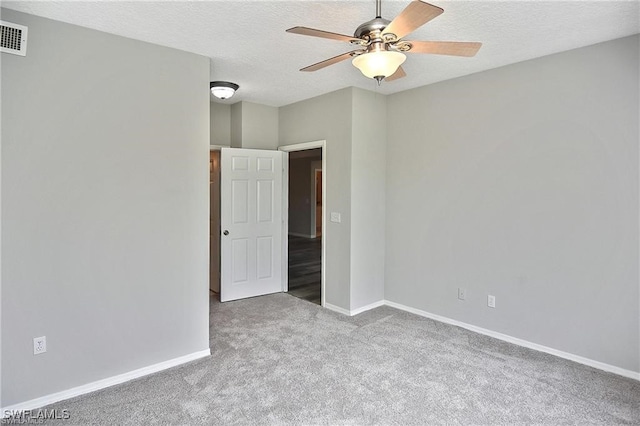 carpeted spare room featuring ceiling fan, baseboards, and a textured ceiling