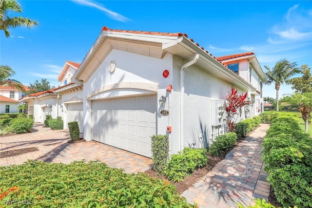 3159 Serena Ln Unit 102, Naples, FL 34114 - view of side of home featuring an attached garage, stucco siding, a tiled roof, and driveway