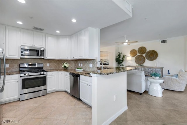 3159 Serena Ln Unit 102, Naples, FL 34114 - kitchen featuring stainless steel appliances, a peninsula, decorative backsplash, dark stone counters, and white cabinetry