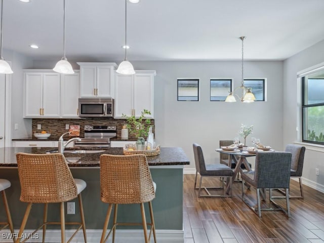 kitchen with stainless steel appliances, backsplash, white cabinets, dark stone counters, and recessed lighting