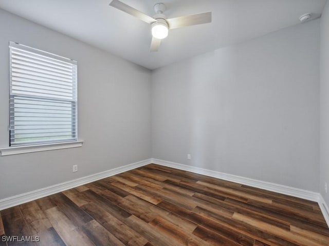 unfurnished room featuring baseboards, dark wood-type flooring, ceiling fan, and a smoke detector