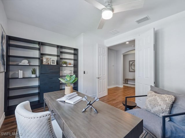 office space with wood finished floors, arched walkways, ceiling fan, and baseboards