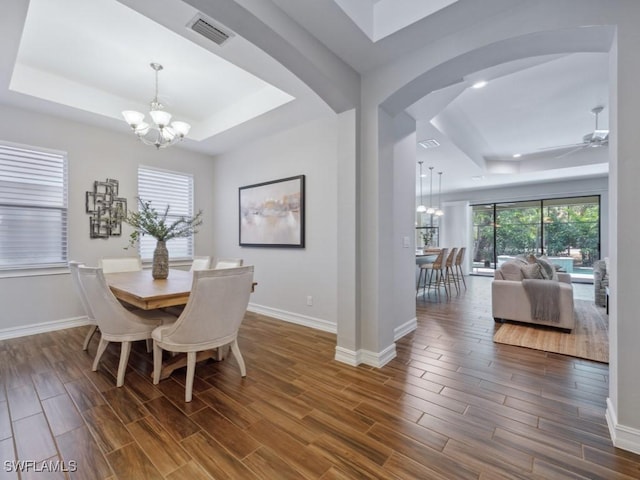 dining room featuring a raised ceiling, a chandelier, wood finished floors, and baseboards
