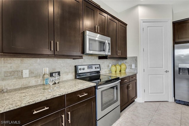 kitchen with stainless steel appliances, dark brown cabinets, light stone countertops, and decorative backsplash