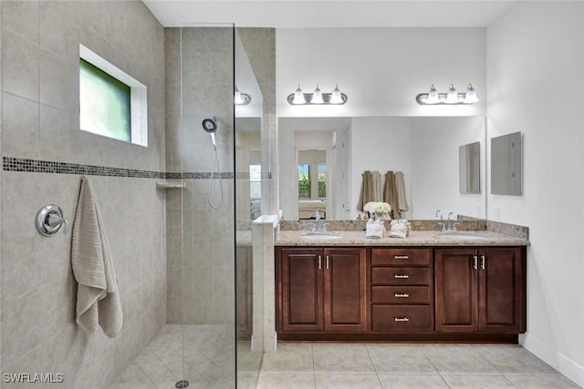 bathroom with plenty of natural light, walk in shower, double vanity, and baseboards