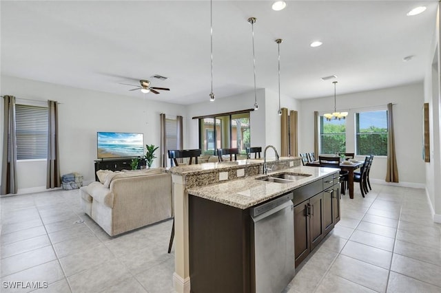 kitchen with stainless steel dishwasher, a sink, light tile patterned floors, open floor plan, and a kitchen island with sink