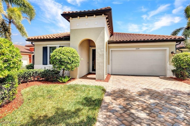 mediterranean / spanish house with stucco siding, a garage, and a tiled roof