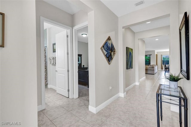corridor featuring light tile patterned floors and baseboards